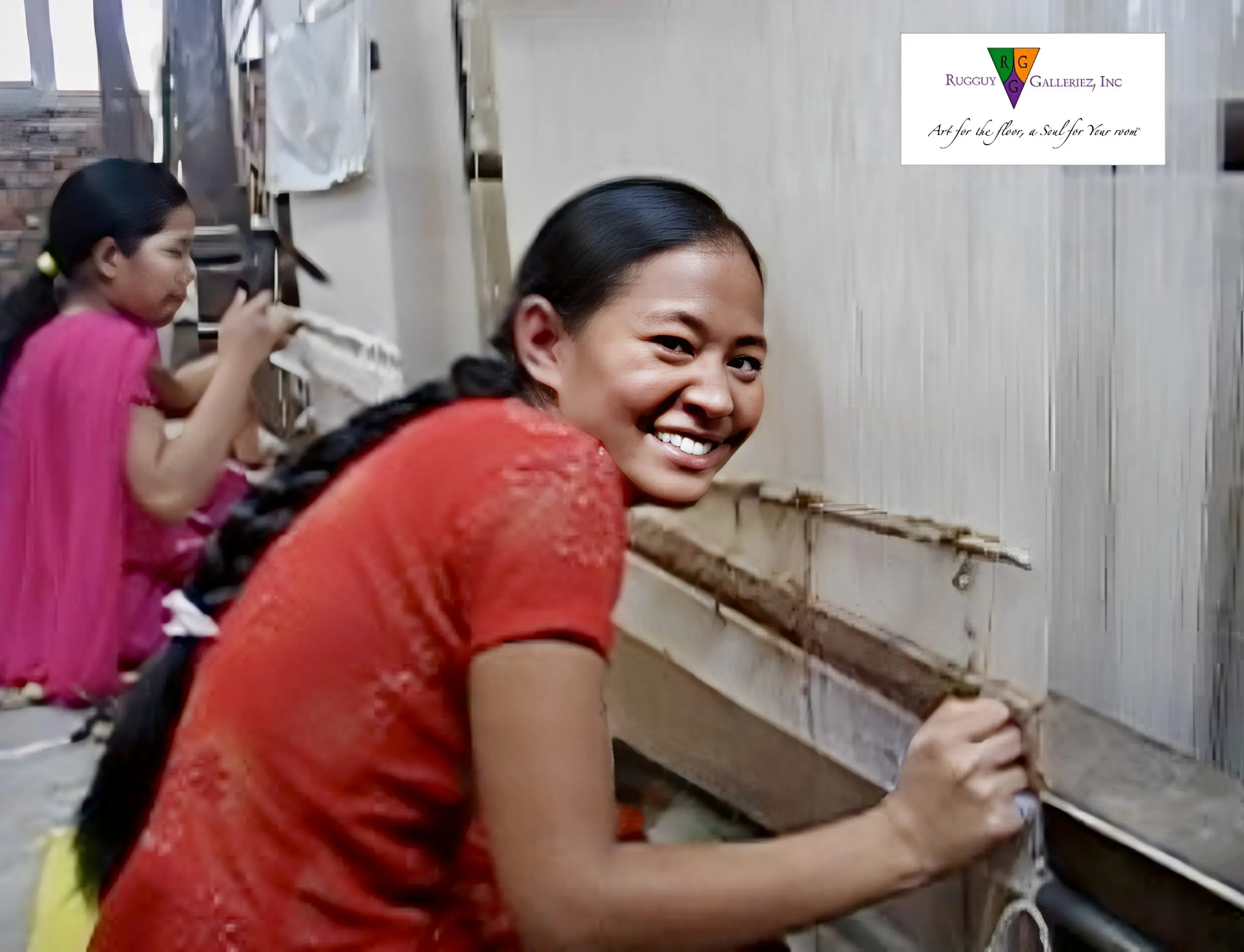 Girls weaving at a loom, smiling together.